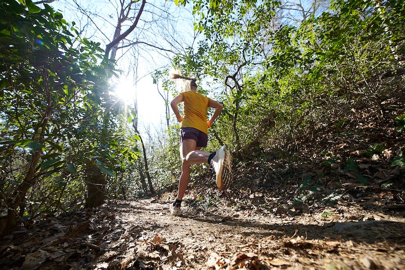 A runner moving along a sunlit trail